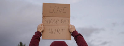 Person holding love should not hurt sign.